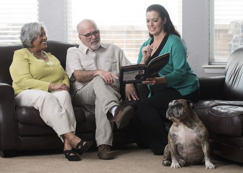 Adult child looking at brochure with parents and dog