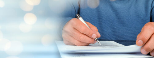 Person with pen in their hand writing on paper