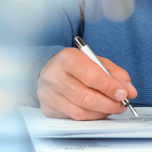 Person with pen in their hand writing on paper