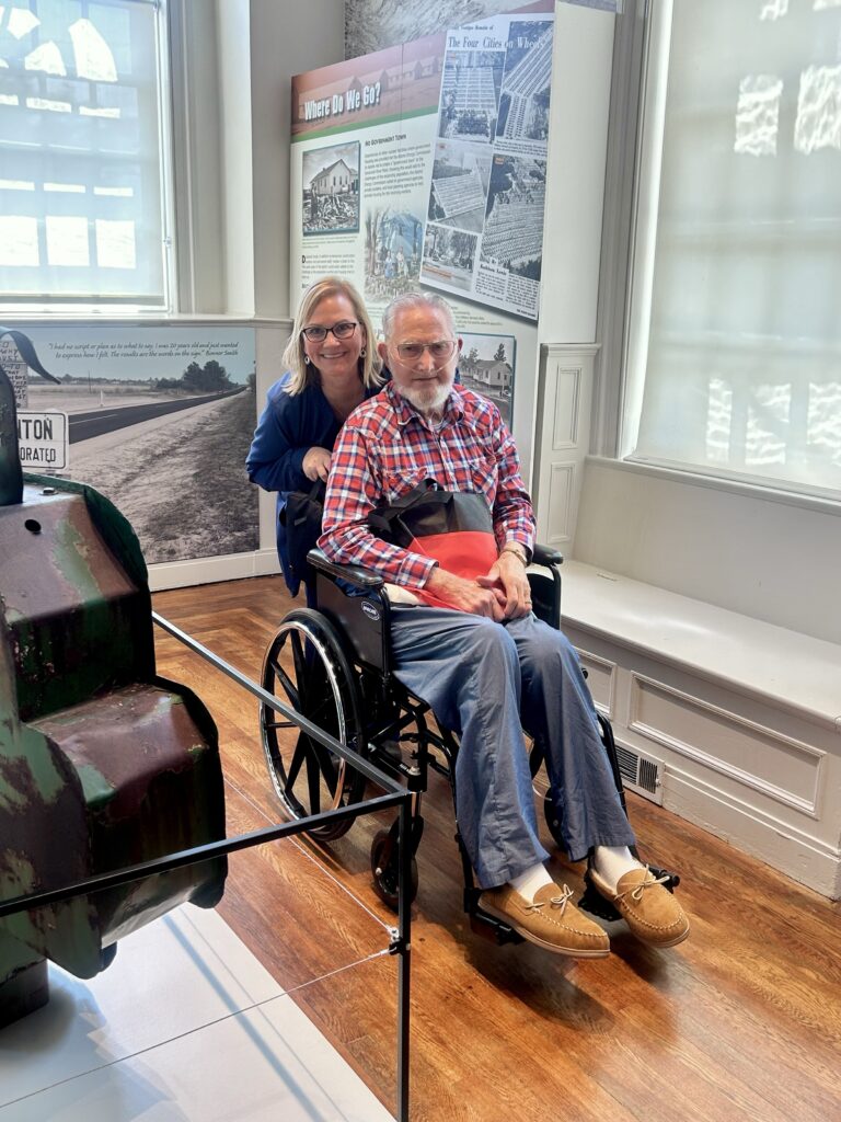 caregiver pushing a man in wheelchair through a museum