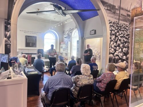 museum guide giving a presentation to people sitting