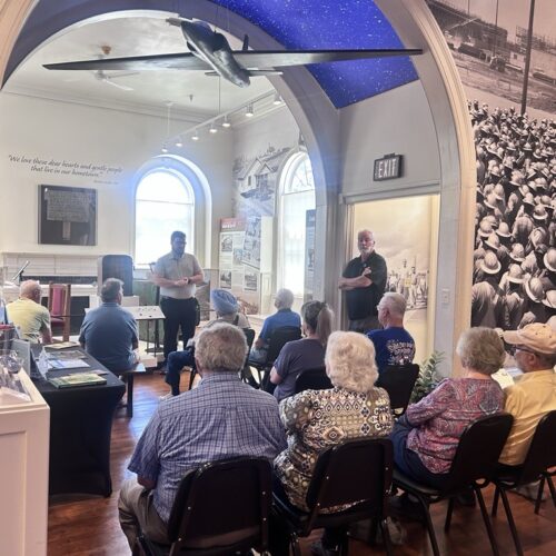 museum guide giving a presentation to people sitting
